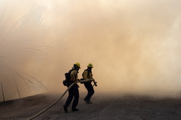 Firefighters move into heavy smoke along Tierra Rejada road as the Easy fire swept into the area in 2019. The use of overtime to fill public safety slots continues to explode in California. (Photo by David Crane/MediaNews Group/Los Angeles Daily News via Getty Images)