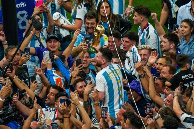 Argentina's Lionel Messi holds the winners trophy as he celebrates with fans after Argentina won the World Cup final soccer match against France at the Lusail Stadium in Lusail, Qatar, Sunday, Dec. 18, 2022. (AP Photo/Francisco Seco)